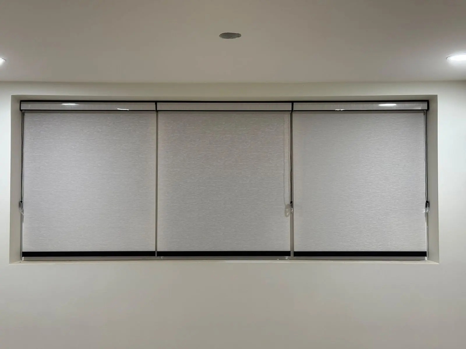Wide triple roller blinds installed across a Winnipeg window